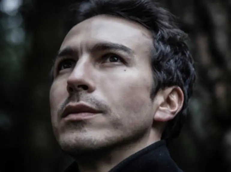 Era el novio de Amelia, un periodista que descubre la relación que tiene la iglesia  con el narco. 