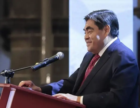 Con el fin de acercar su grabadora de audio, la reportera extendió su brazo por arriba del hombro del político.