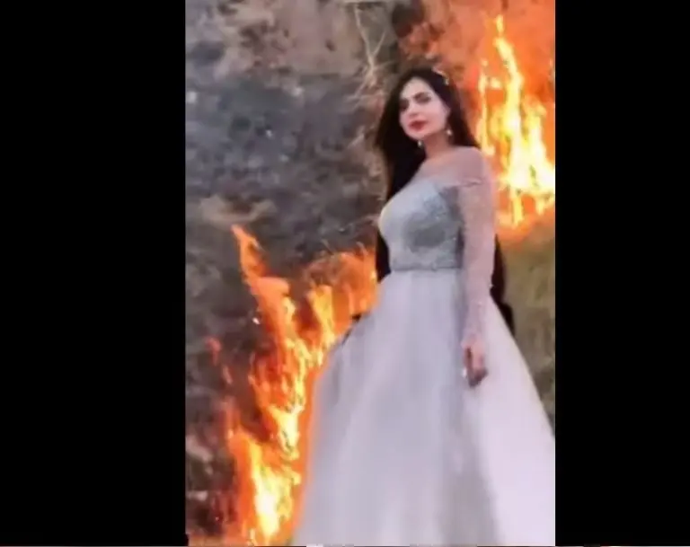 La joven aparece posando mientras detrás de ella sucede un incendio forestal.