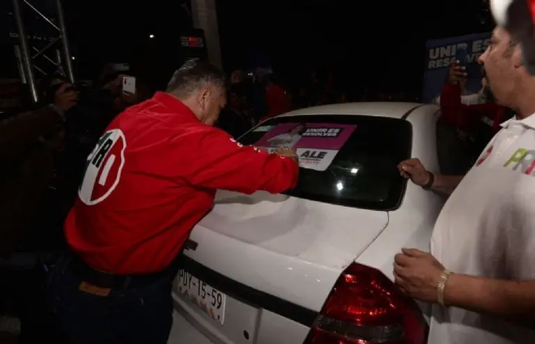 Alito Moreno pegando estampas de la campaña electoral en los autos. Créditos: PRI