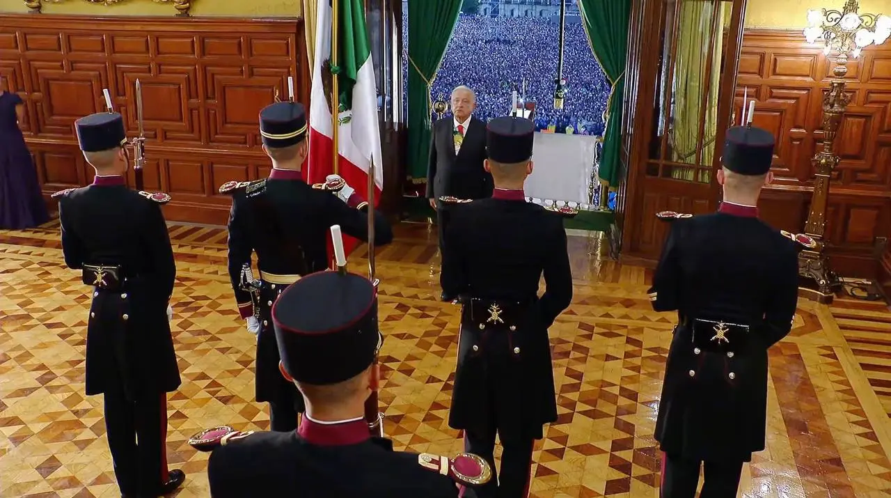 El presidente López Obrador se acerca para recibir la bandera mexicana.<br>