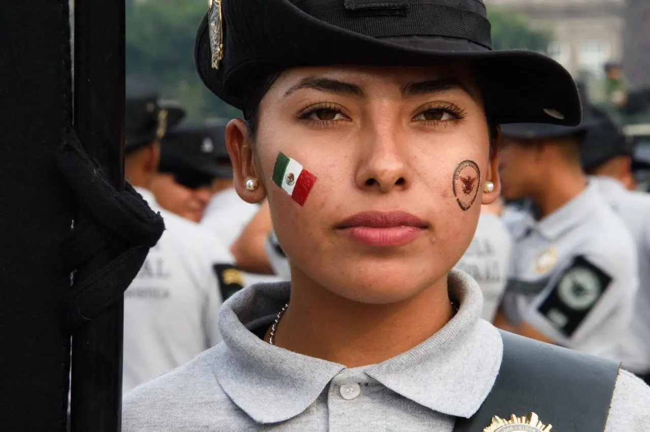 Elemento de la Guardia Nacional con la bandera en una mejilla y el símbolo de la GN en la otra.<br>