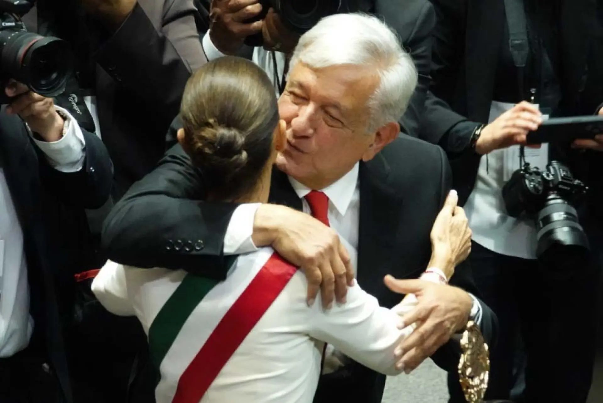 Claudia Sheinbaum porta la banda presidencial, momento en el que AMLO le da un segundo abrazo.
