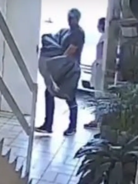 En el video se le observa subiendo las escaleras con un bulto con forma humana envuelto en una cobija. Captura de pantalla.