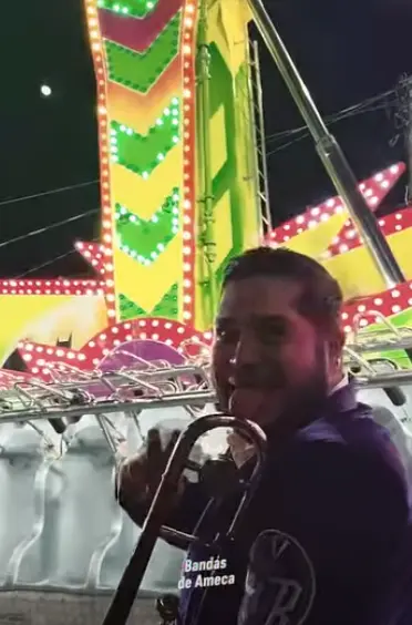 El clip muestra a cuatro músicos interpretando trombones y clarinete dentro de la atracción conocida como Kamikaze, un juego tipo péndulo que se balancea a considerable altura. Captura de pantalla.