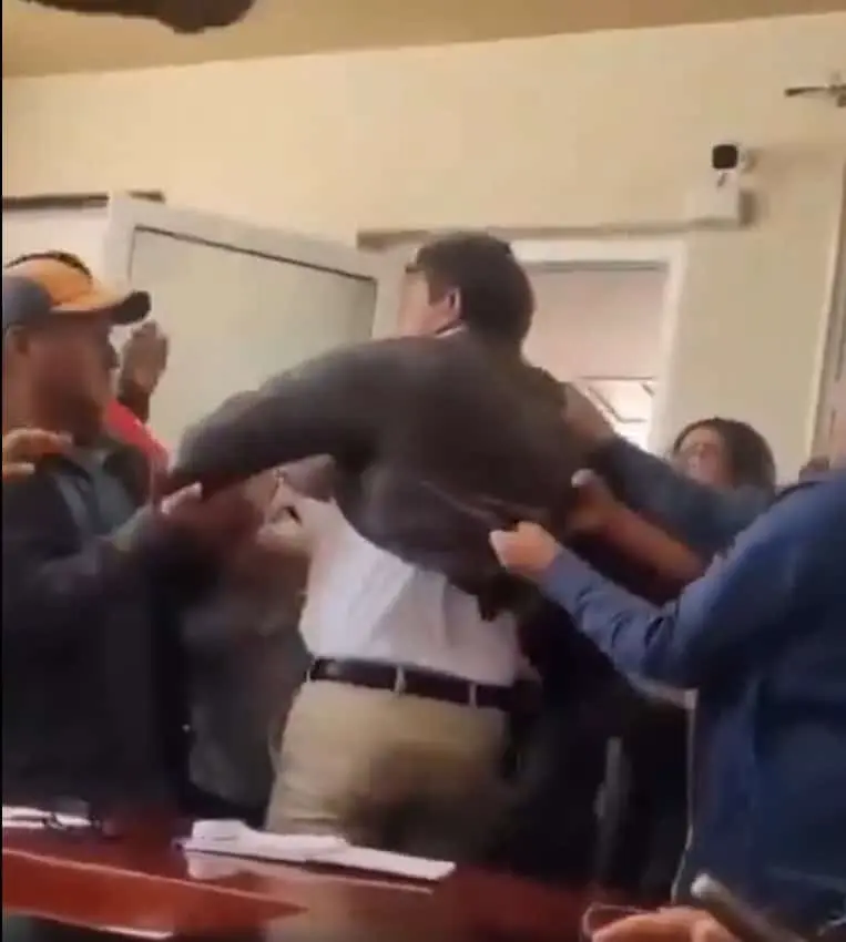 En medio de la tensión, el presidente municipal es conducido hacia el exterior del inmueble entre jaloneos y empujones. Captura de pantalla.